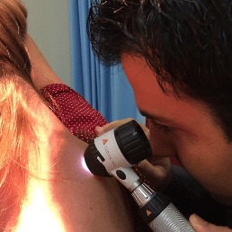 Dr Fred Fotouhi examining mole on patients body for potential skin cancer