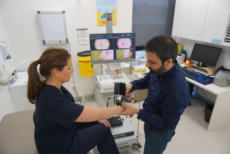 Dr Fred Fotouhi, a skin cancer doctor examines a patients forearm with a dermatoscope to diagnose skin lesions and diseases, such as melanoma.